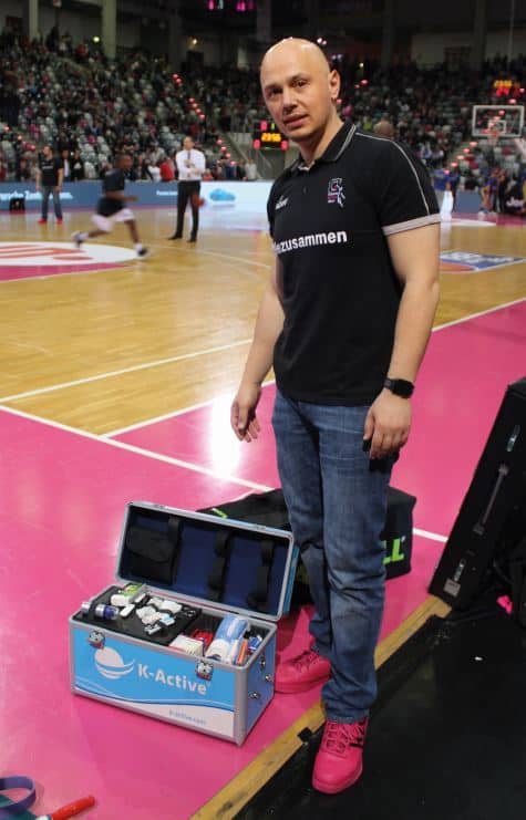 Bogdan Suciu mit K-Active Koffer vor Basketballfeld